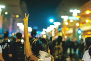 person making peace sign with hand in street