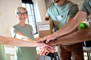 A group of volunteers putting their hands together and smiling